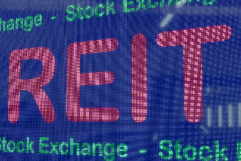 Close-up of a digital display showing the word "REIT" in red, with "Stock Exchange" in green text above and below.